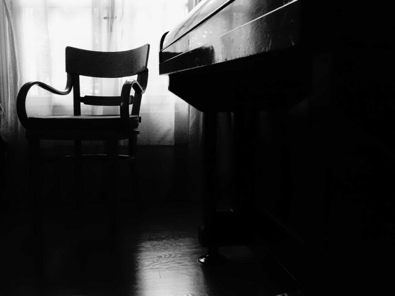 Μια καρέκλα και ένα γραφείο σε σιλουέτα κόντρα σε φωτεινό παράθυρο, σε σκοτεινό δωμάτιο.